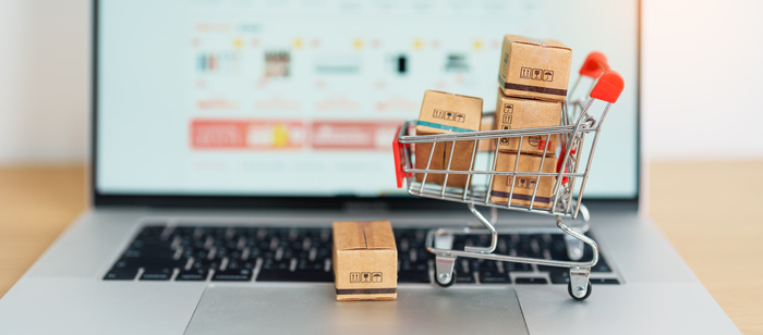 Boxes with shopping cart on a laptop computer. Ecommerce website open on laptop